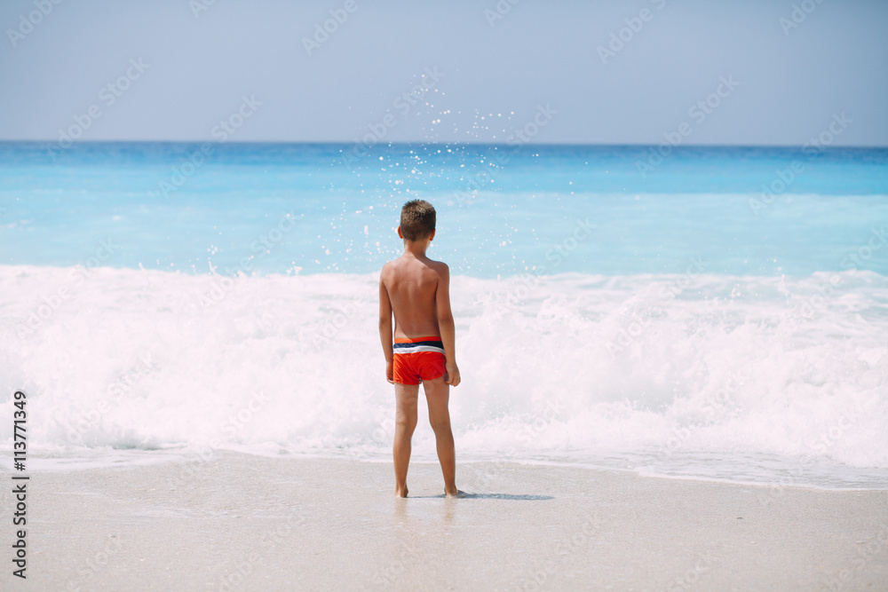 Beach vacation dream. Handsome young boy enjoying in beautiful tropical beach, standing and playing with waves. Beach vacation dream. Handsome young boy enjoying in beautiful tropical beach, standing and playing with waves.