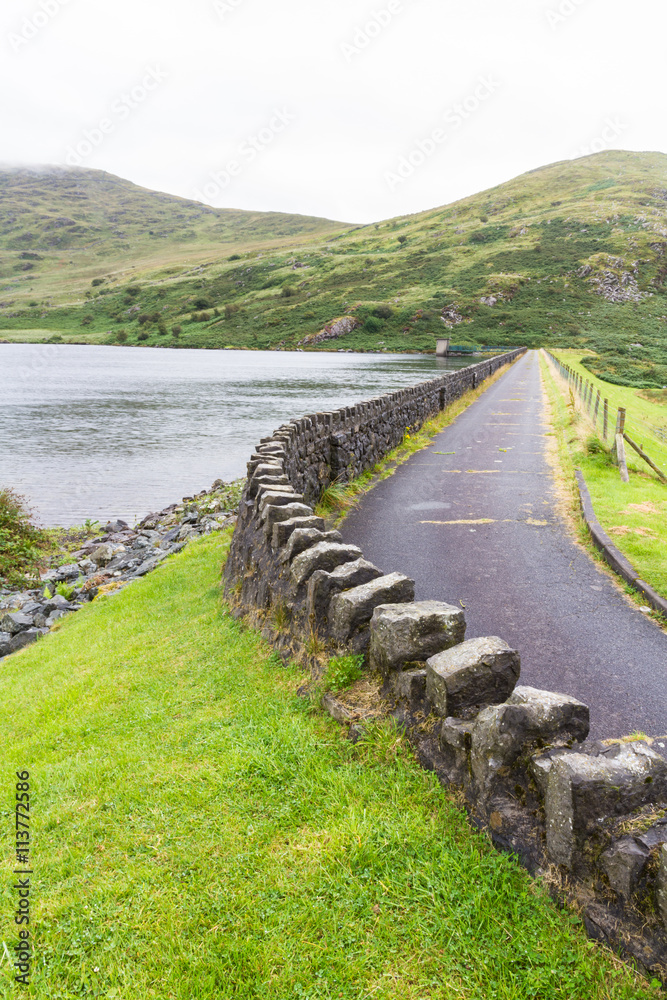 Obraz premium Road over dam of Llyn Cwmystradllyn reservoir.