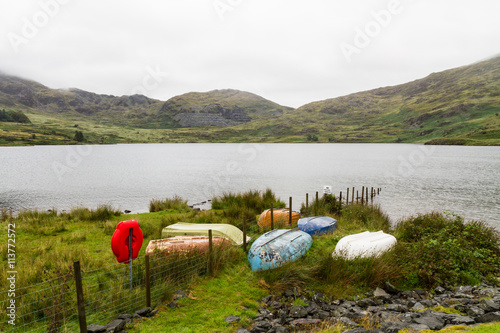 Different coloured rowing boats on bank of reservoir. photo