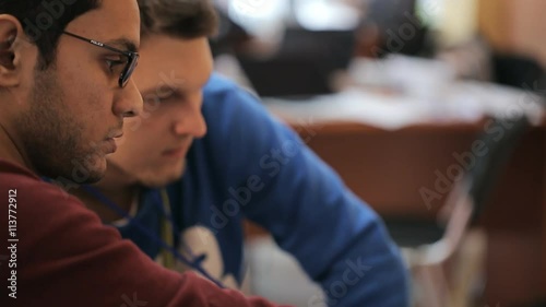 Serious man in glasses earnestly says something to guy in a hoodie