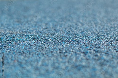 Colorful blue Rubber Wetpour playground floor surface, shot low down with narrow depth of field. © mikesmithdesign
