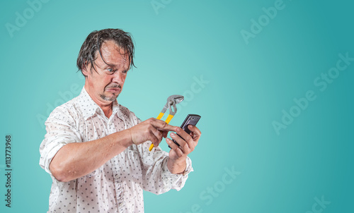 Canvas Print nasser Mann mit Wasserpumpenzange sucht auf Smartphone nach Hilfe