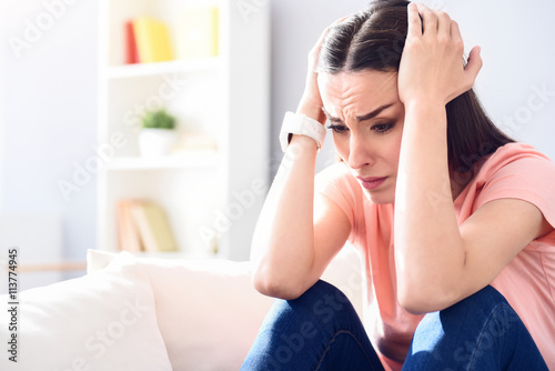 Gloomy disappointed woman sitting on the couch