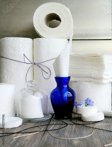 White kitchen paper towel, toilet paper, paper tissues ,cotton disks on a dark wooden table