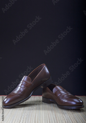 Mens Brown Penny Loafer Shoes Against Black Background
