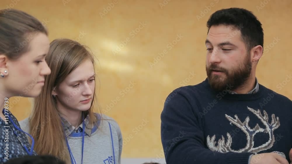 A bearded man in a sweater, gesturing, urges two girls in expediency of his decision A bearded man in a sweater, gesturing, urges two girls in expediency of his decision