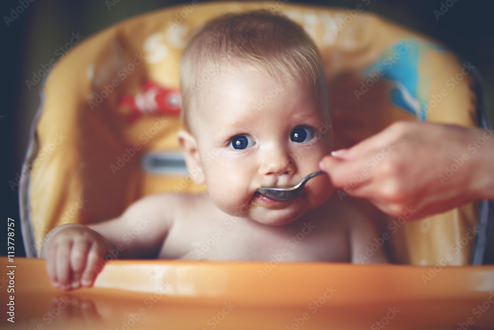mother feeding baby boy with a spoon mother feeding baby boy with a spoon