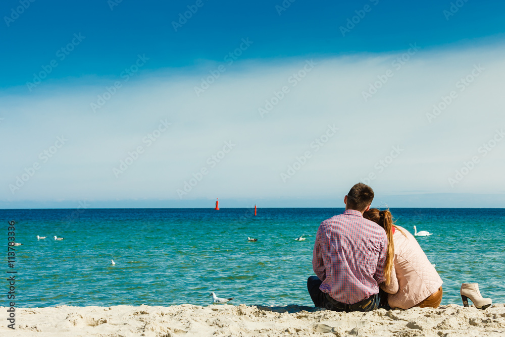 couple sitting on beach rear view