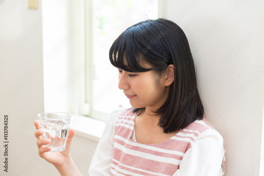部屋で水を飲む女性 部屋で水を飲む女性