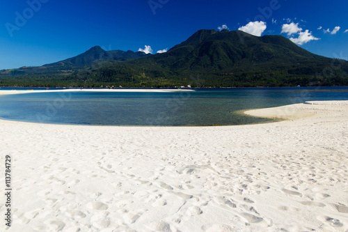Island with white sand and volcano in the background