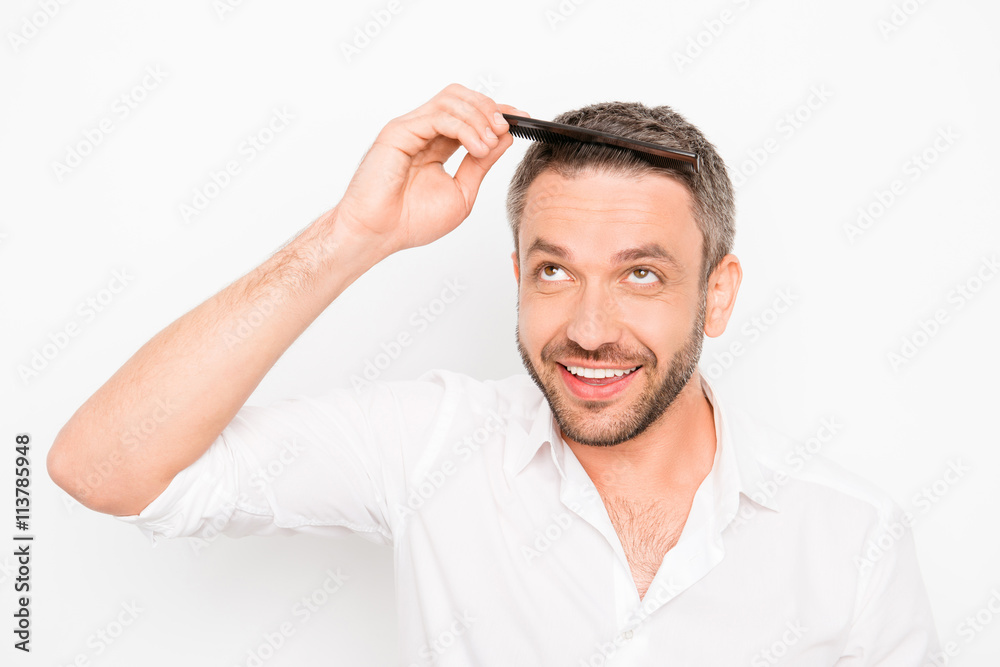 Handsome young man combing his hair with comb Handsome young man combing his hair with comb