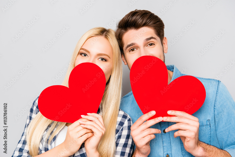 Portrait of man in woman hiding faces behind paper hearts Portrait of man in woman hiding faces behind paper hearts