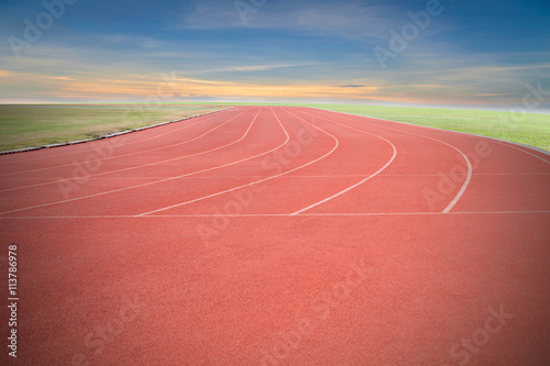  Running track with green grass and blue sky white cloud backgro