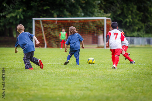 Boys playing soccer with goalkeeper in the background