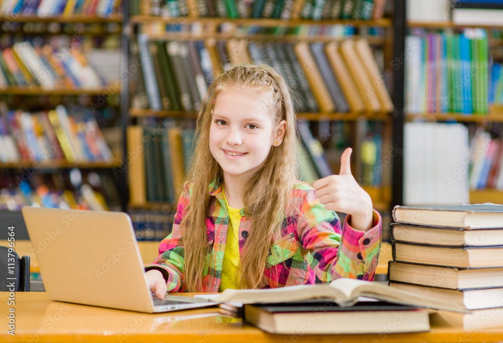 teen girl with laptop in library showing thumbs up teen girl with laptop in library showing thumbs up