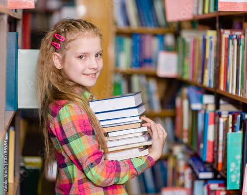 teen girl with pile books in the library