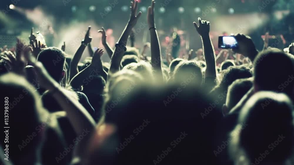 Iconic night rock concert front row crowd cheering slomo 100p.Night rock concert.People cheer move lift and clap their hands in unison against the strobing stage lights.