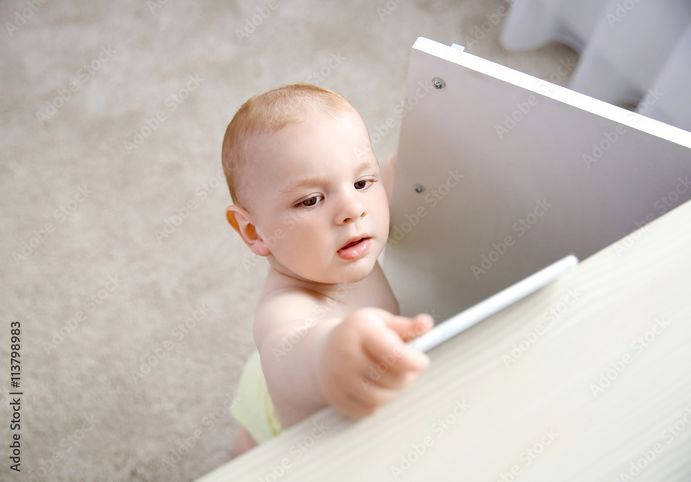 Baby boy taking smartphone from the cupboard Baby boy taking smartphone from the cupboard