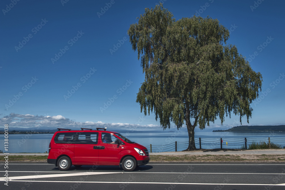 Φωτογραφία A red car driving along the coast of Lake Taupo in North Island of New Zealand