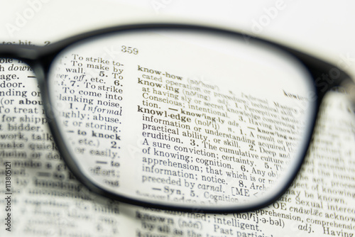 knowledge word in dictionary, close up, view through nearsighted lens glasses