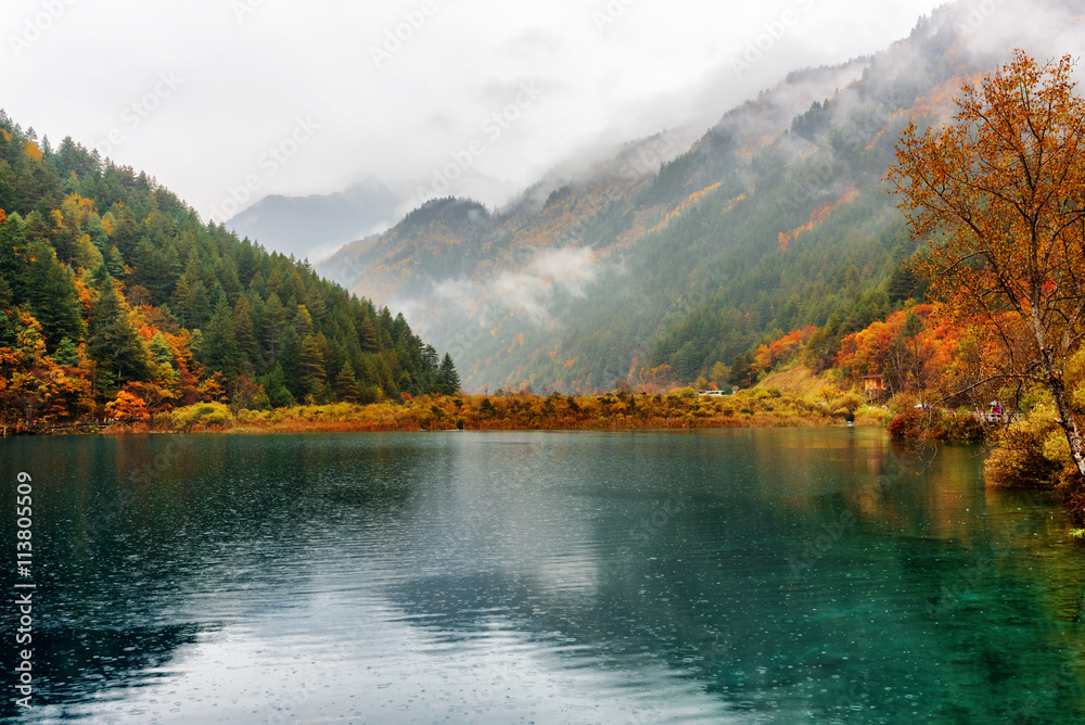 Scenic view of the Tiger Lake among colorful fall forest in rain