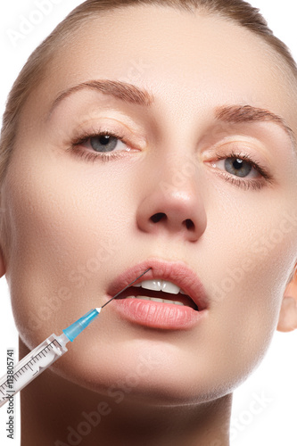 Portrait of young woman getting cosmetic injection. Closeup of beautiful woman gets injection in her face. Filler injections. Lip augmentation. Beautiful perfect lips