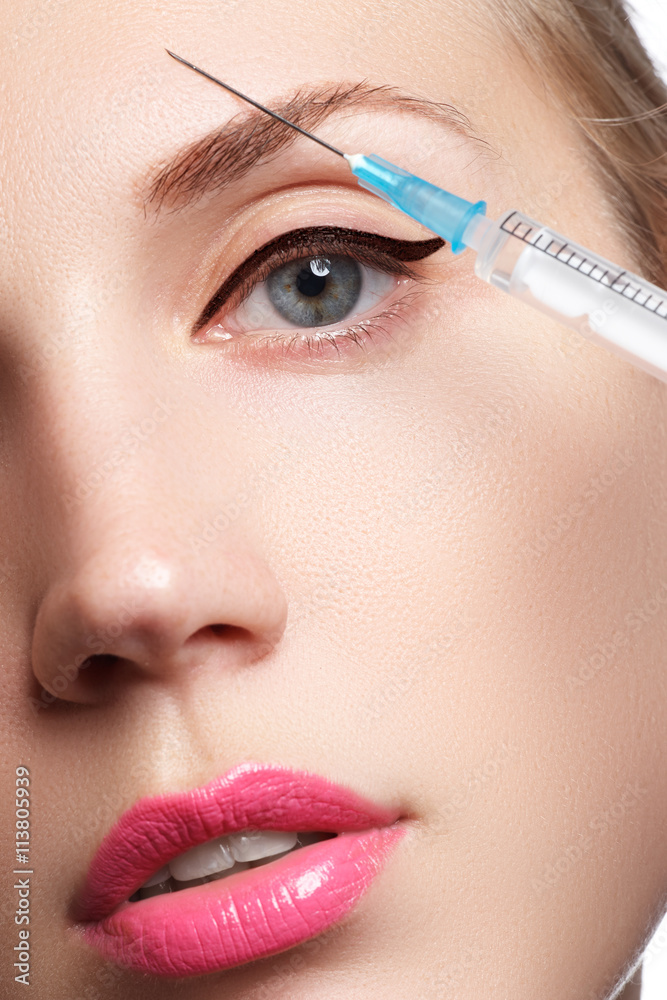 Portrait of young woman getting cosmetic injection. Closeup of beautiful woman gets injection in her face. Filler injections. Lip augmentation. Beautiful perfect lips


