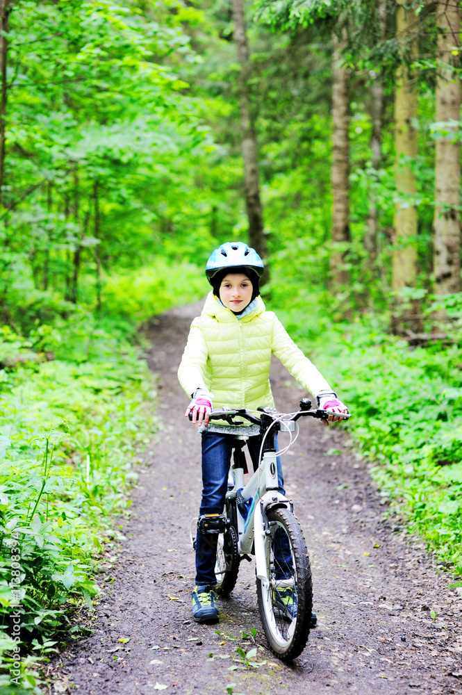 Little girl riding on bicycle in the forest