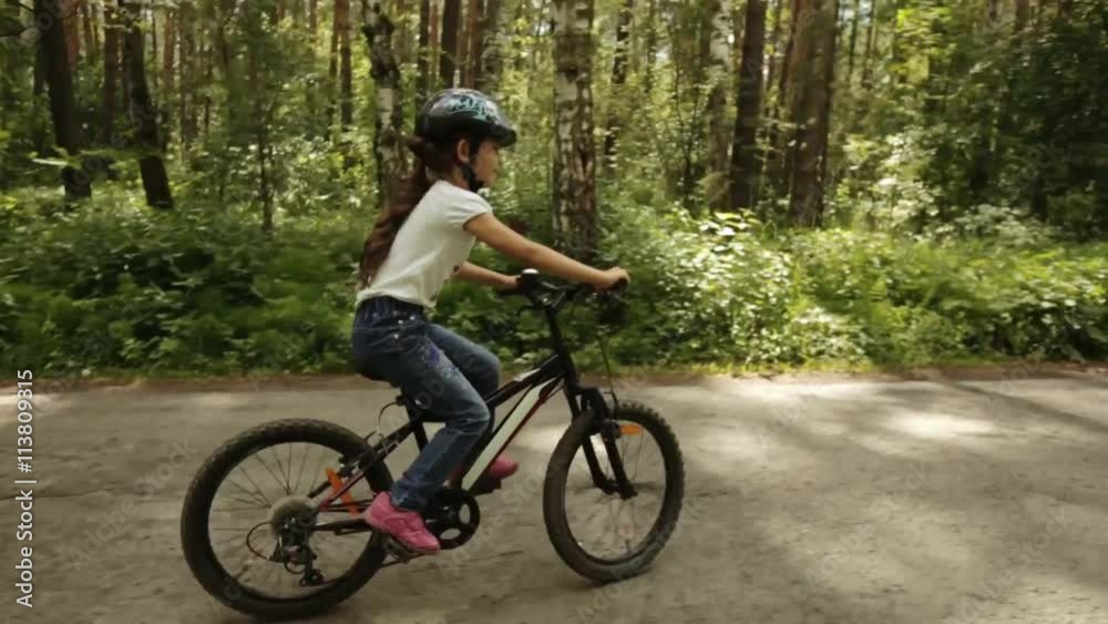 little girl rides her bike on a forest trail little girl rides her bike on a forest trail