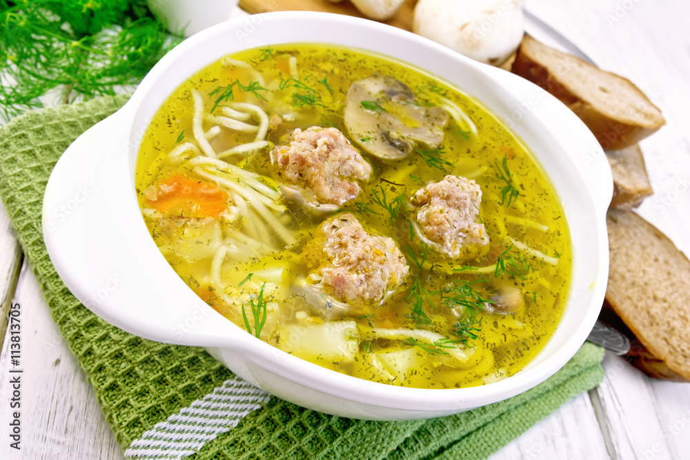Soup with meatballs and noodles in bowl on green napkin Soup with meatballs and noodles in bowl on green napkin
