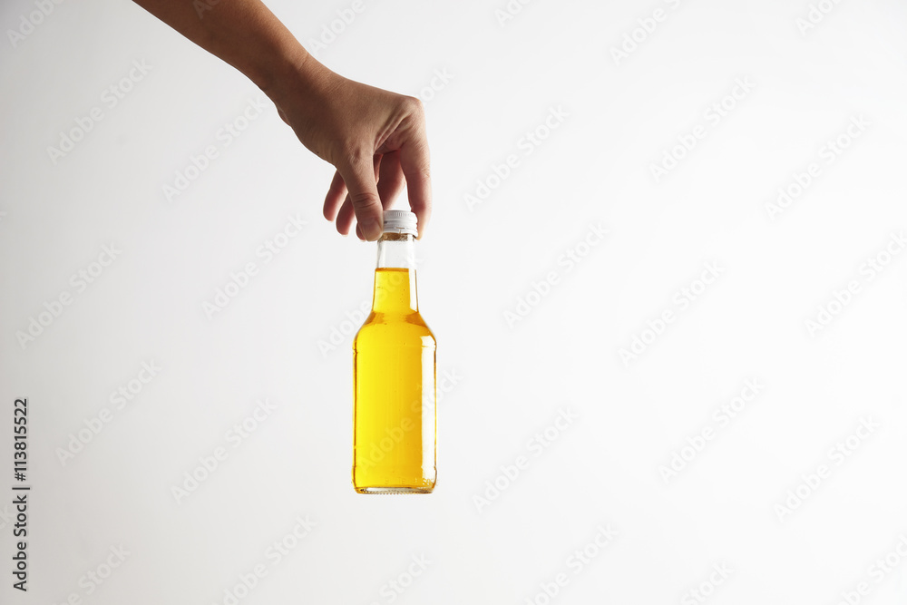 Hand puts down closed rustic glass bottle with tasty cold drink inside, isolated on white in center Hand puts down closed rustic glass bottle with tasty cold drink inside, isolated on white in center