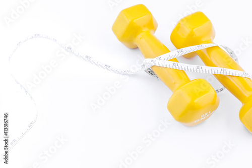 Fitness equipment . Yellow dumbbell with measuring tape on white