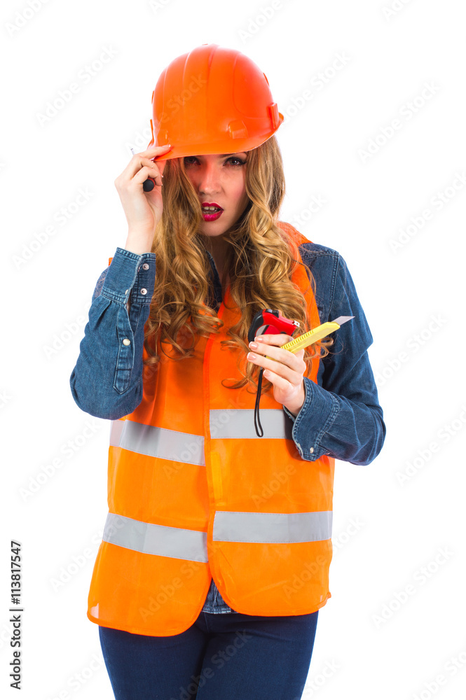 Young woman architect in an orange vest and hardhat holding tools: tape measure, building knife, screwdriver. Woman engineer in special clothes on a white background. Young woman architect in an orange vest and hardhat holding tools: tape measure, building knife, screwdriver. Woman engineer in special clothes on a white background.