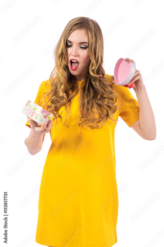Young pretty girl with blonde hair in a yellow dress holding a gift. Beautiful girl with a gift in hand on white background. Young pretty girl with blonde hair in a yellow dress holding a gift. Beautiful girl with a gift in hand on white background.