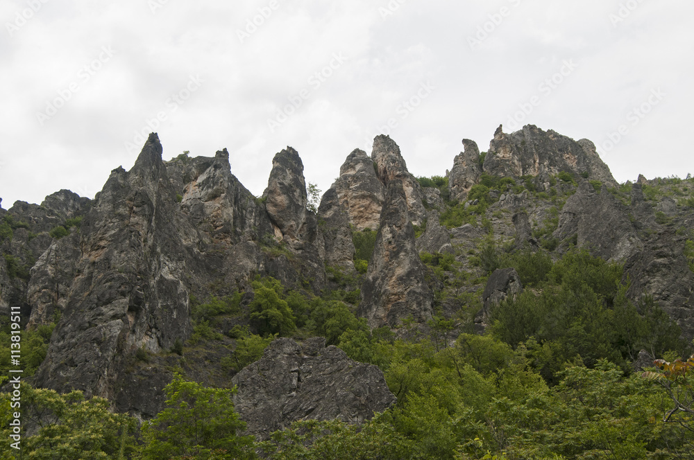 Eroded rocks in mountains against gray cloudy sky background