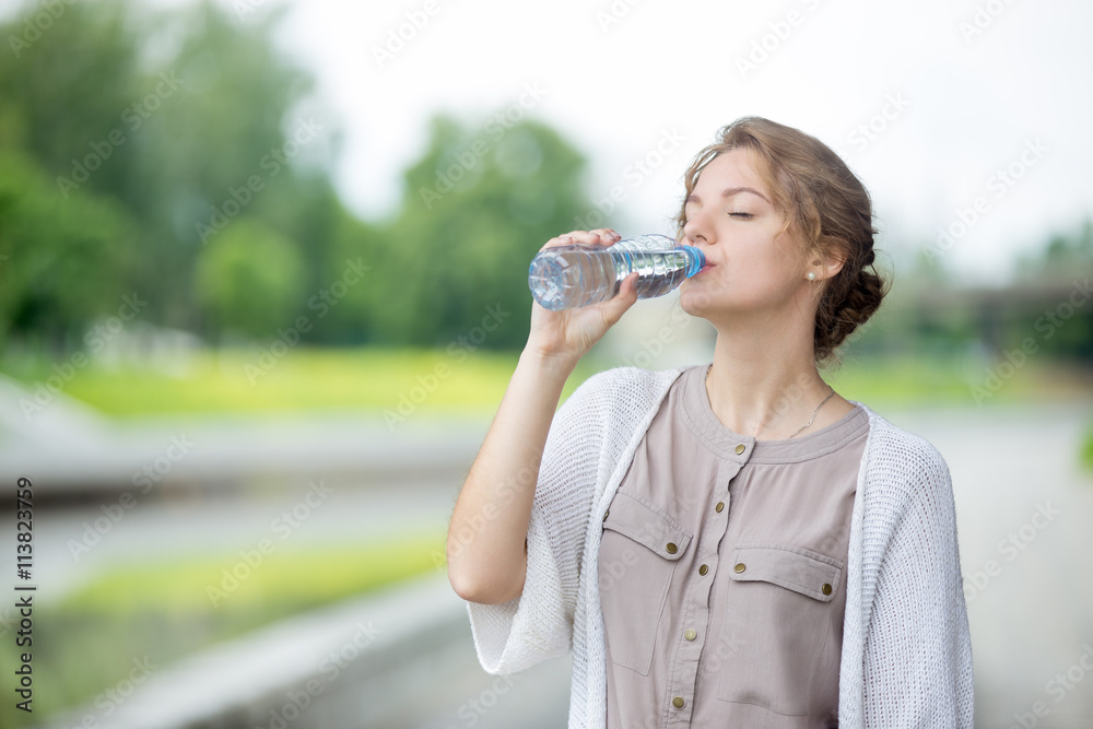 Lifestyle headshot portrait of beautiful woman drinking water with closed eyes. Young female standing on the street and enjoying bottled water in summer. Thirsty attractive caucasian model Lifestyle headshot portrait of beautiful woman drinking water with closed eyes. Young female standing on the street and enjoying bottled water in summer. Thirsty attractive caucasian model