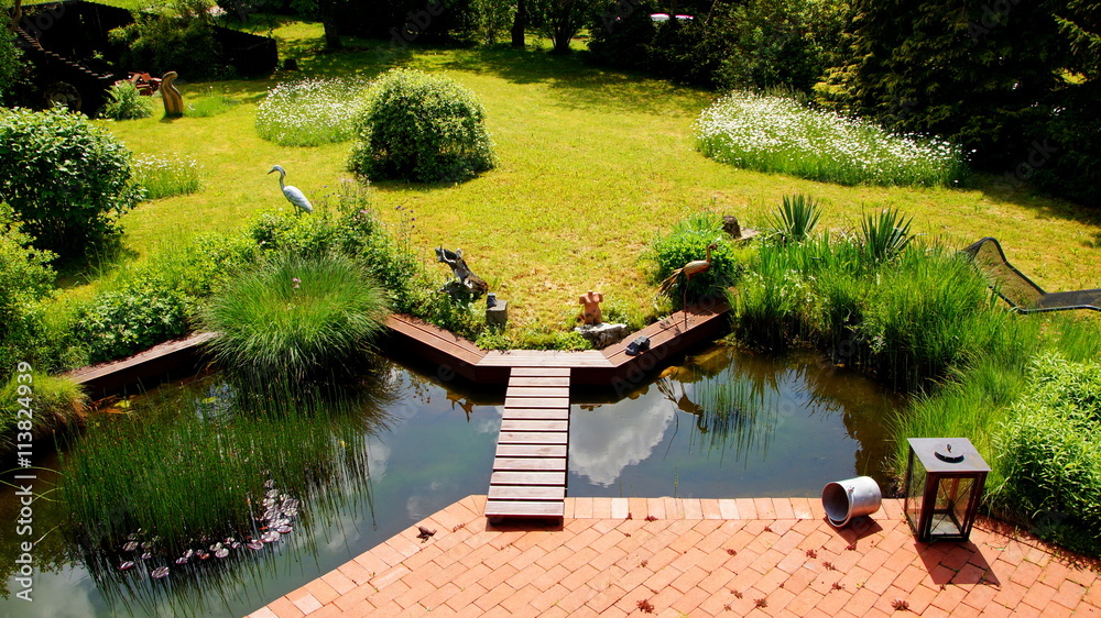 attraktiver naturbelassener Garten mit an Terrasse angrenzenden Teich