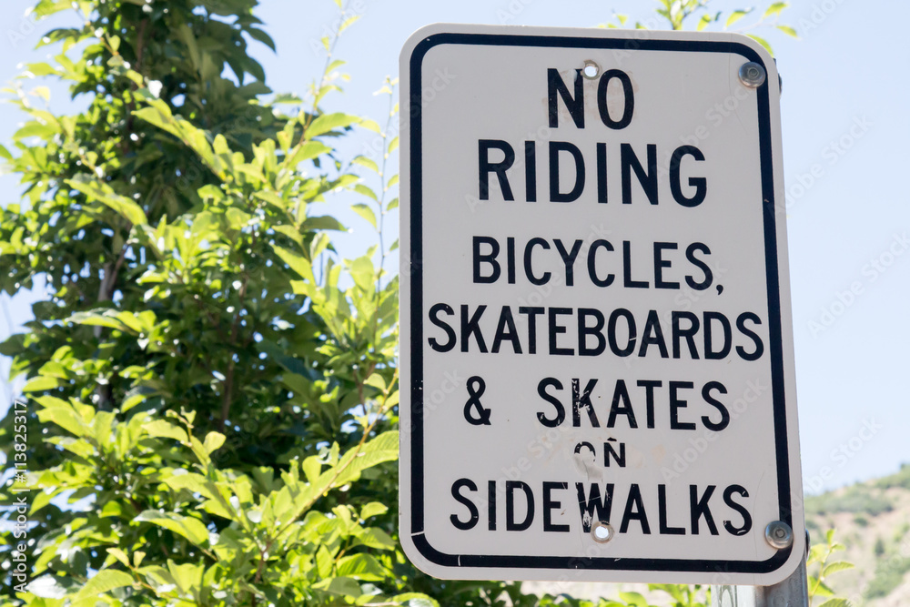 Sign for no riding bicycles, skateboards and skates on sidewalk Sign for no riding bicycles, skateboards and skates on sidewalk