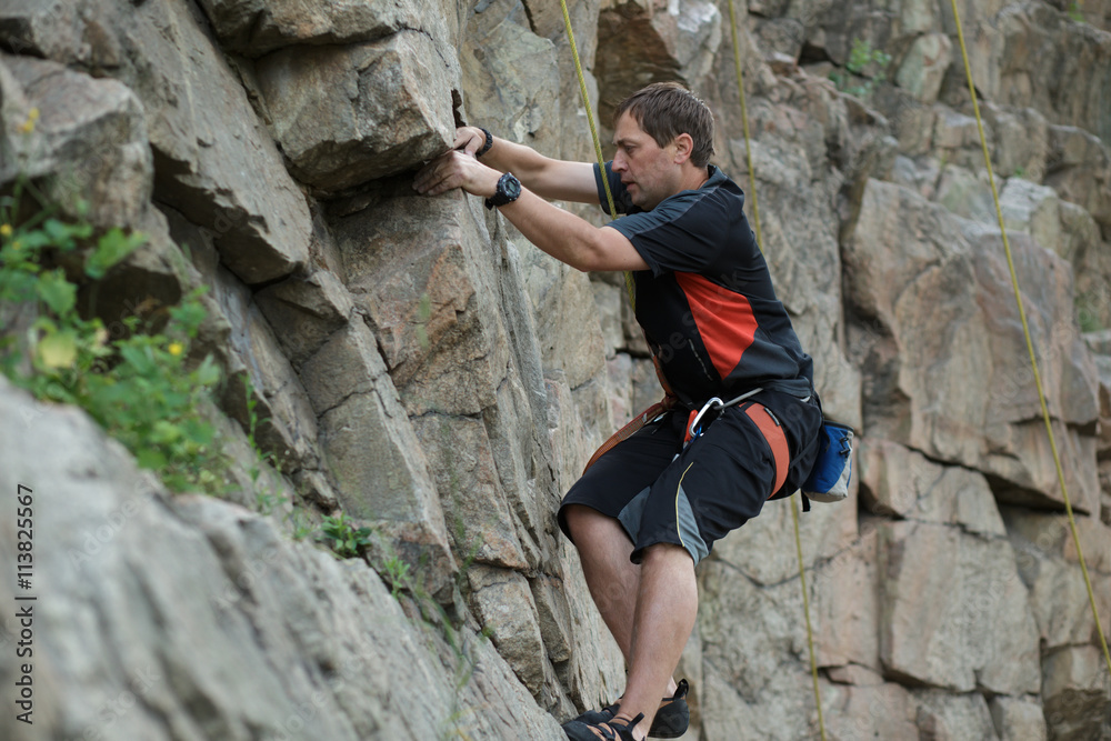 Male rock climber clings to a cliff Male rock climber clings to a cliff