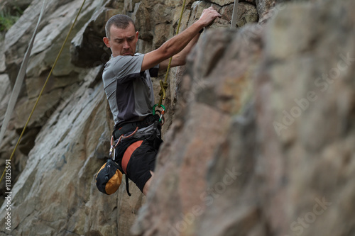 Male rock climber clings to a cliff