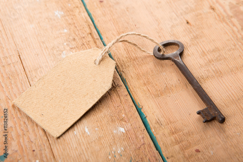 Old rusty key with a paper label on the wooden board