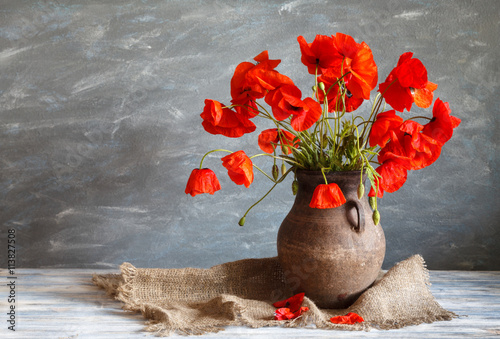 Fototapeta Naklejka Na Ścianę i Meble -  Still life in a rustic style: an old crock and a bouquet of red poppies on a wooden table
