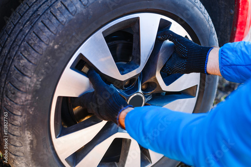 Fotografie Man repairing car wheel on the street