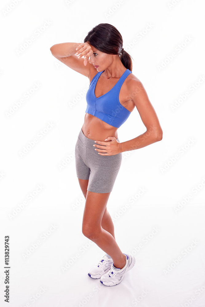 Standing brunette woman wiping her brow Standing brunette woman wiping her brow