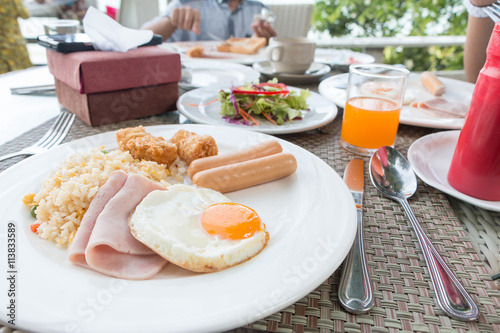 Breakfast with fired rice, fried egg, ham, sausage, fired fish,