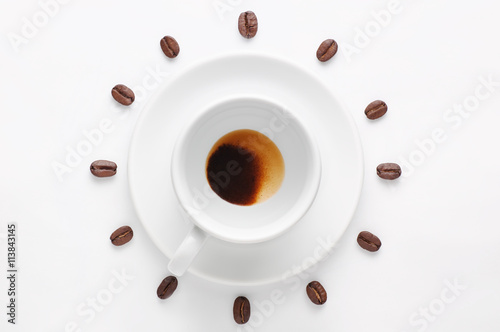 Drunk cup of coffee and coffee beans against white background forming clock dial viewed from top