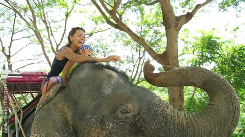 Mom and daughter feeding elephant with banana. Mom and daughter spend time in the travel.
