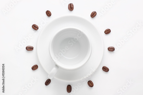 Empty coffee cup and coffee beans against white background forming clock dial viewed from top