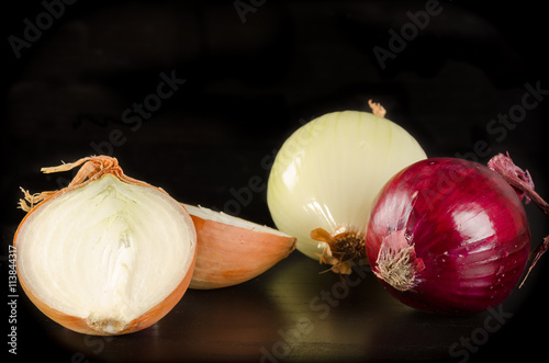 Variety of onions on black wooden background