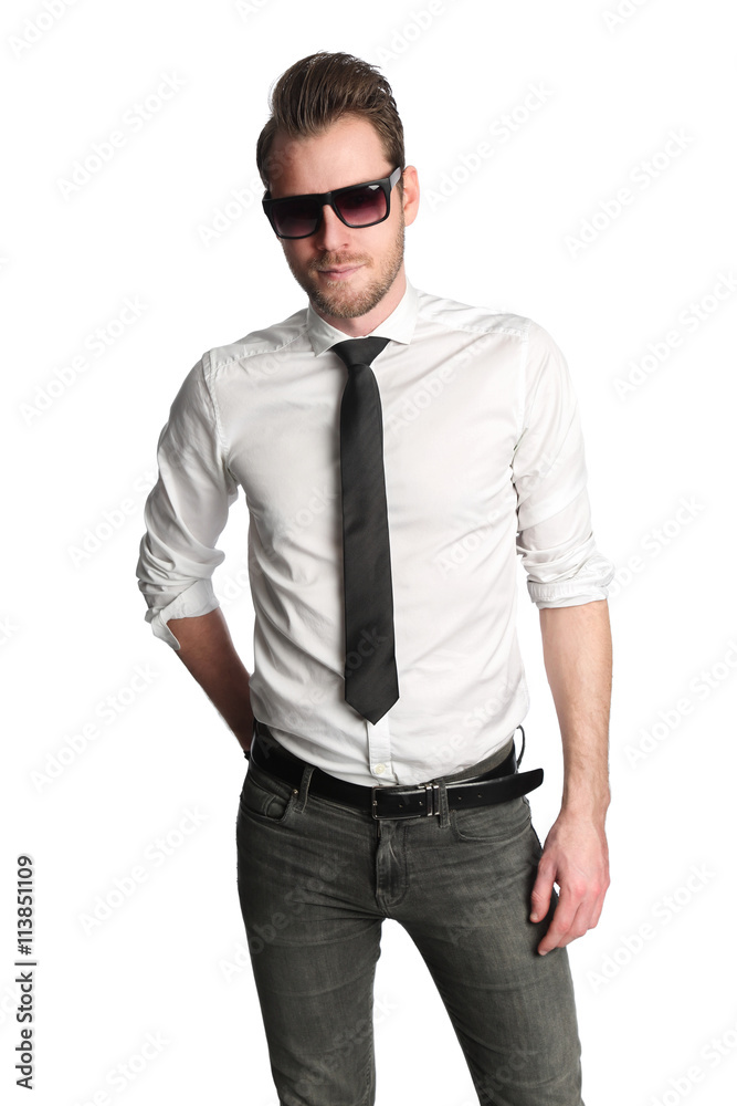 A trendy focused man wearing dark sunglasses, a white shirt with a black tie  and jeans, standing against a white background. Stock Photo | Adobe Stock